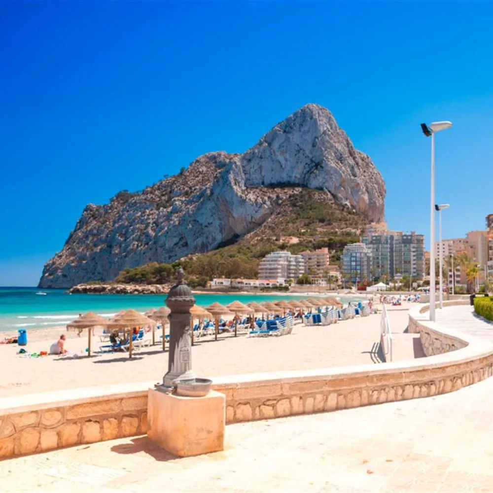 Calpe beach promenade and Penon de Ifach in bright Mediterranean weather